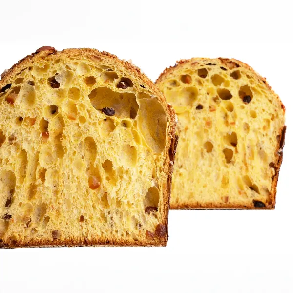Deux tranches de panettone montrant une mie jaune et alvéolée, parsemée de raisins.