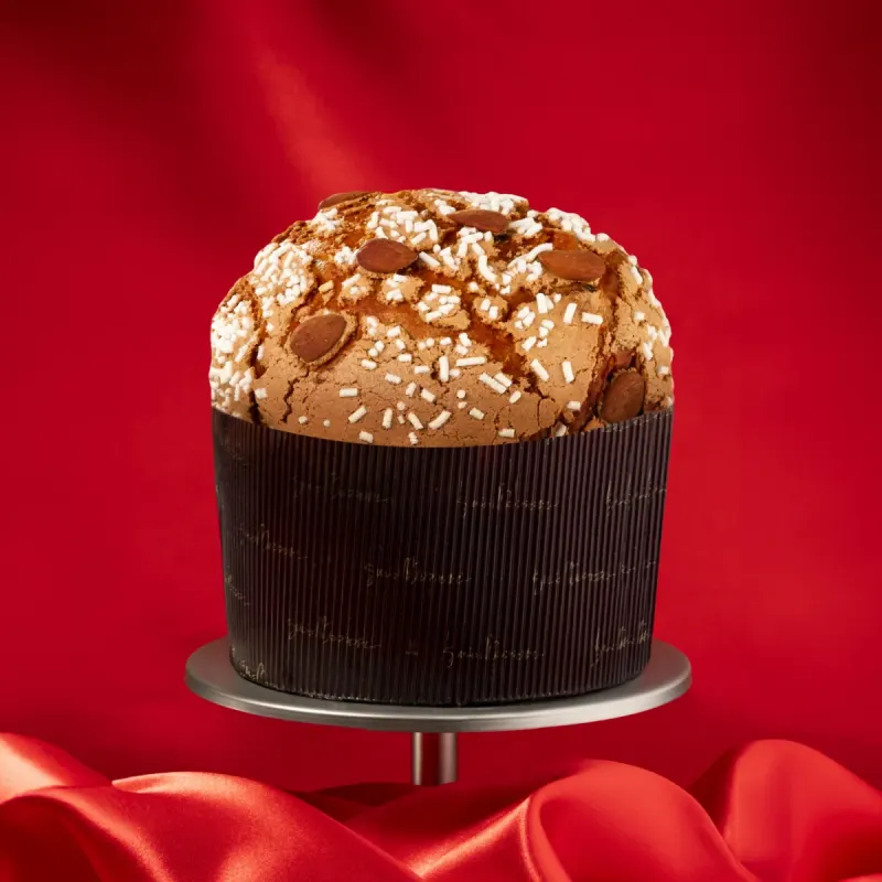 Panettone Iginio Massari, dôme glacé aux amandes, présenté sur fond rouge.